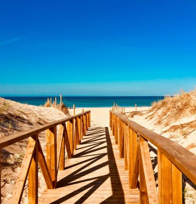 A serene wooden walkway leading to a peaceful beach in Vejer de la Frontera, Spain.