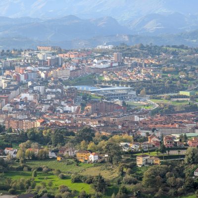 pexels-photo-29574523-29574523-1 Breathtaking aerial view of Oviedo's cityscape with mountainous background and lush greenery.